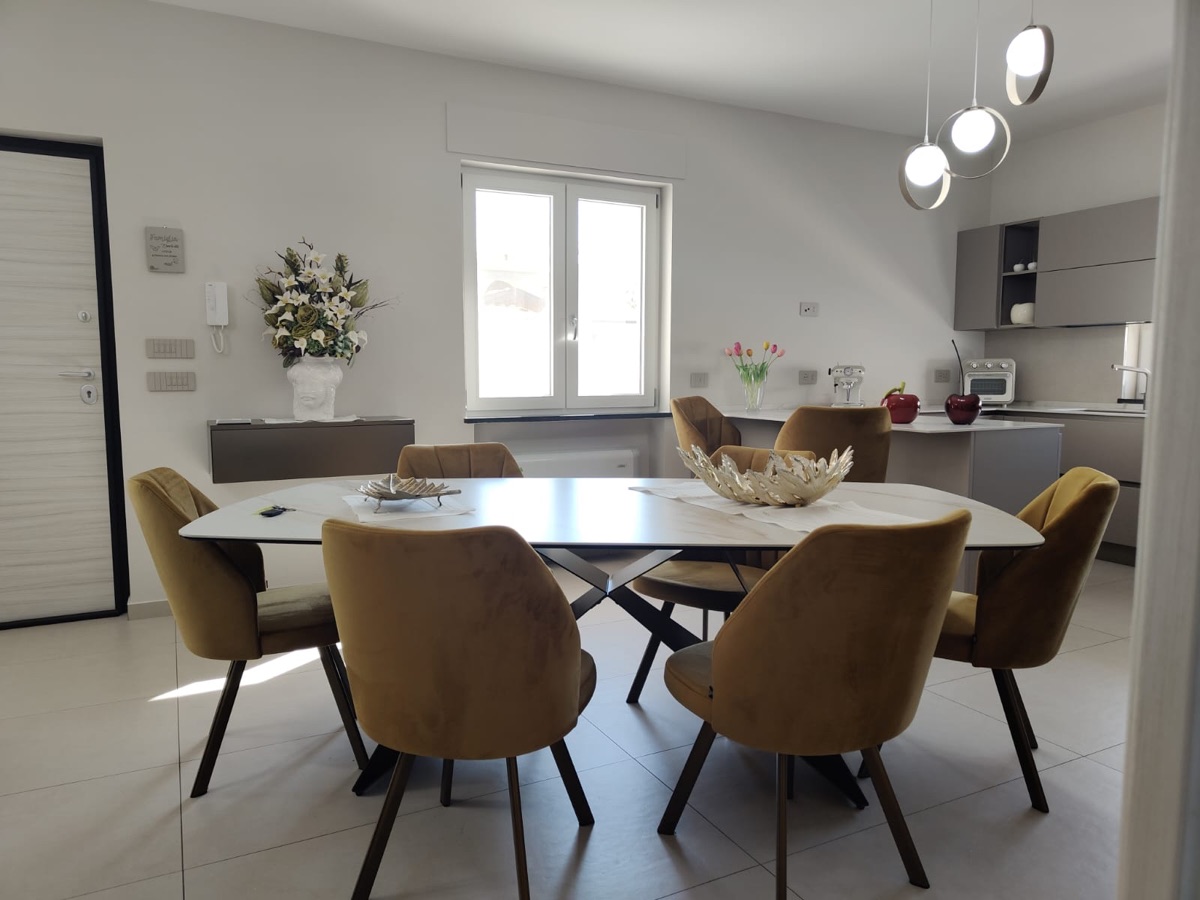 Zona pranzo con tavolo ovale e sedute ocra, realizzazione Molitierno Arredamenti