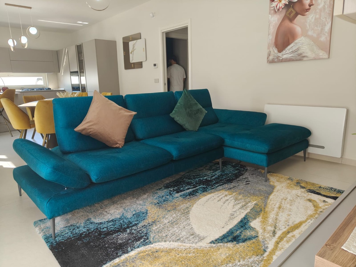 Living con divano turchese e cucina a vista, realizzazione Molitierno Arredamenti